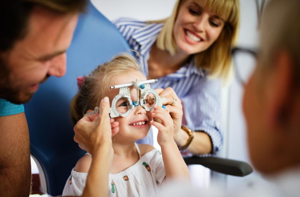 Little girl wearing trial frames at the optometrist clinic, with her parents next to her.